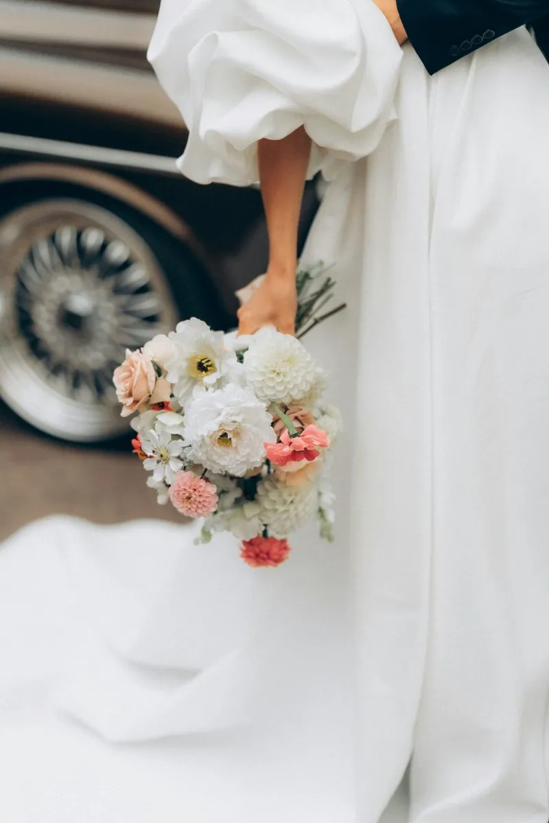Taxi mariage Bordeaux — mariée avec bouquet devant voiture de luxe